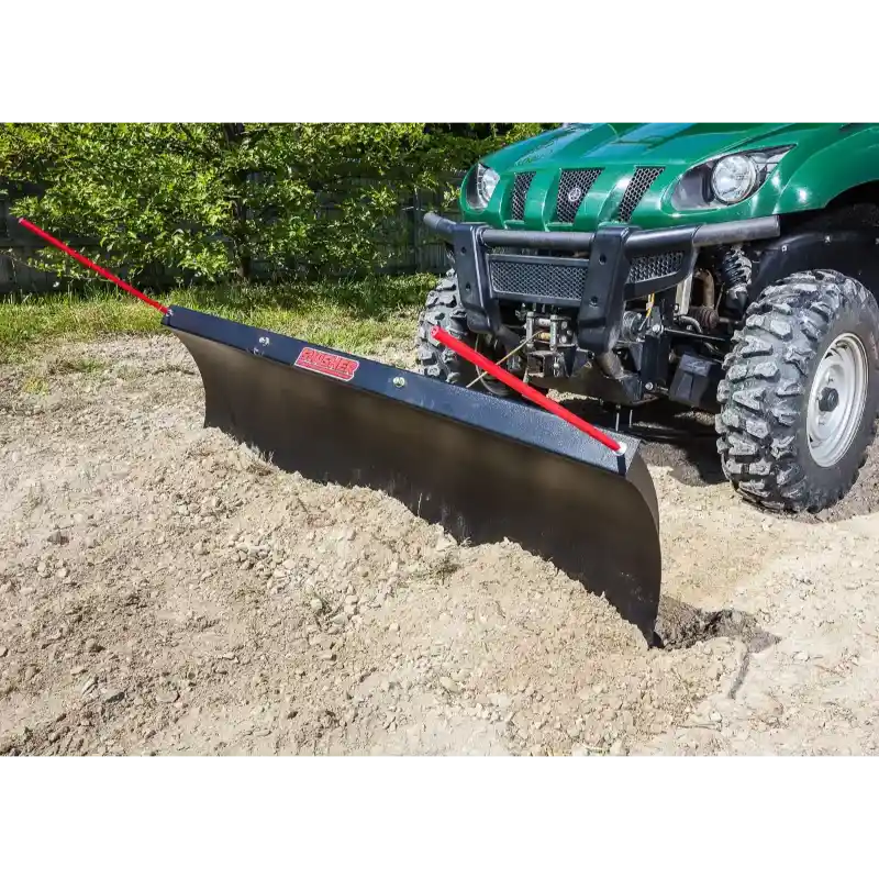 Green utility vehicle with Swisher 62-inch rolled blade plow attached, clearing soil in outdoor setting gallery position 1