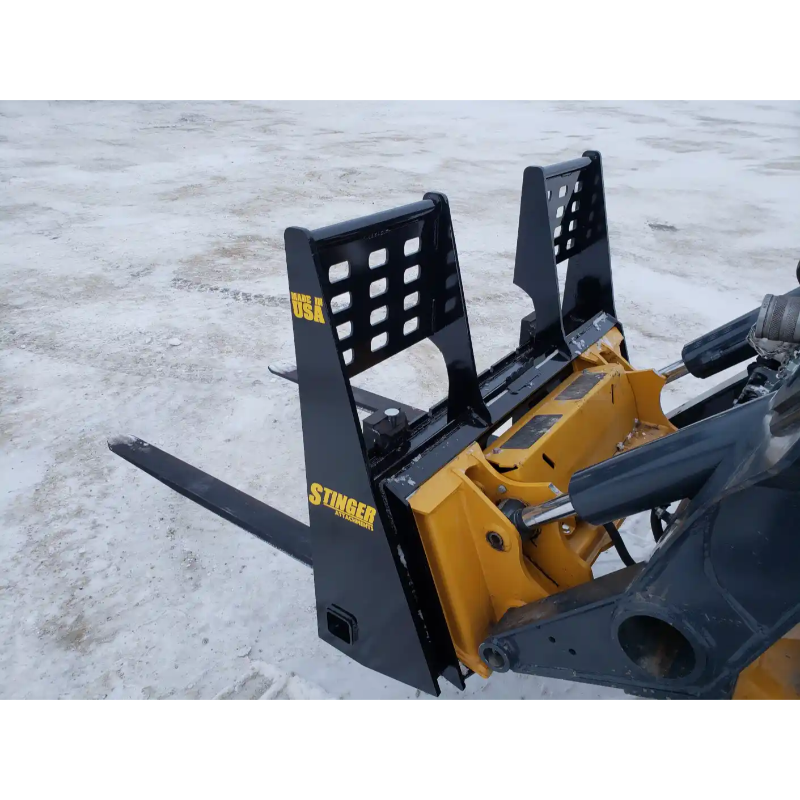Black painted steel skid steer pallet forks attachment with reinforced backrest and two fork tines on dirt surface