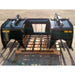 Black painted steel manure tine grapple attachment with dual hydraulic cylinders and spaced tubular tines outdoors on pallet