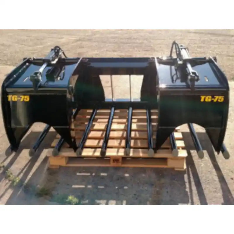 Black painted steel manure tine grapple attachment with dual hydraulic cylinders and spaced tubular tines outdoors on pallet