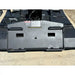 Black steel skid steer hydraulic attachment plate with hoses and warning label on dirt surface