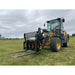 Yellow and black loader with skid steer pallet fork attachment on grass under cloudy sky