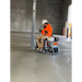 Operator seated on a ride-on power trowel smoothing a large concrete floor inside a building under construction