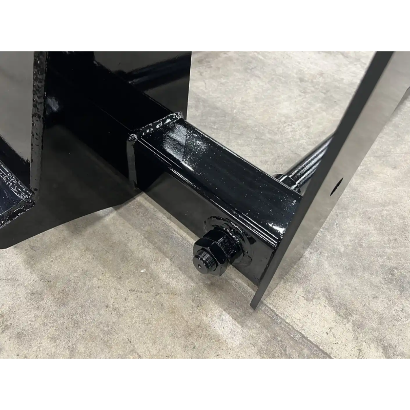 Close-up of glossy black steel skid steer bale spear attachment mounting bracket and bolt on concrete floor