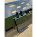 Close-up of black skid steer snow bucket attachment with mounting brackets and rectangular ventilation slots on gravel surface