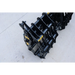 Black steel grapple attachment with hinge mechanism and tubular bars resting on a concrete surface outdoors