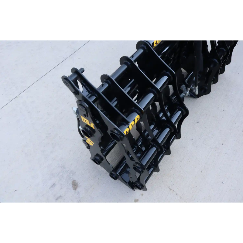 Black steel grapple attachment with hinge mechanism and tubular bars resting on a concrete surface outdoors