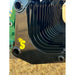 Close-up of black metal rock grapple with curved tines and yellow stinger logo on side over dry grass background