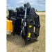Close-up of black hydraulic loader clam-style grapple attachment with visible cylinder and latch on grassy field