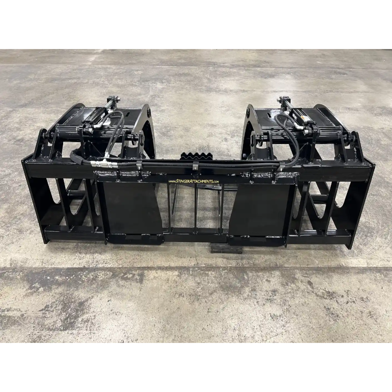 Black steel skid steer grapple attachment with dual hydraulic cylinders and reinforced tine frame on concrete floor