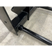 Close-up of black metal frame with welded joints on concrete floor, showing structural components of equipment attachment.