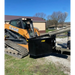 Yellow CASE skid steer with black steel concrete bucket attachment receiving concrete from chute outdoors