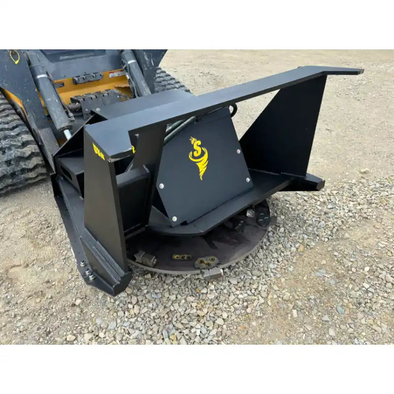 Black metal disc mower attachment with yellow logo mounted on skid steer loader on gravel surface