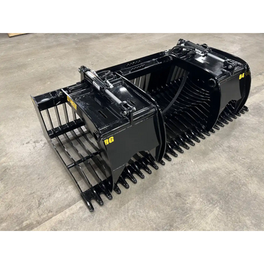 Black steel skid steer rock grapple attachment with dual hydraulic cylinders and spaced curved tines on concrete floor