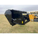 Black steel hydraulic tractor dump bucket attachment tilted back with visible hydraulic cylinders on grass field