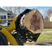 Yellow loader equipped with black hydraulic clam-style grapple attachment holding large cut tree log outdoors