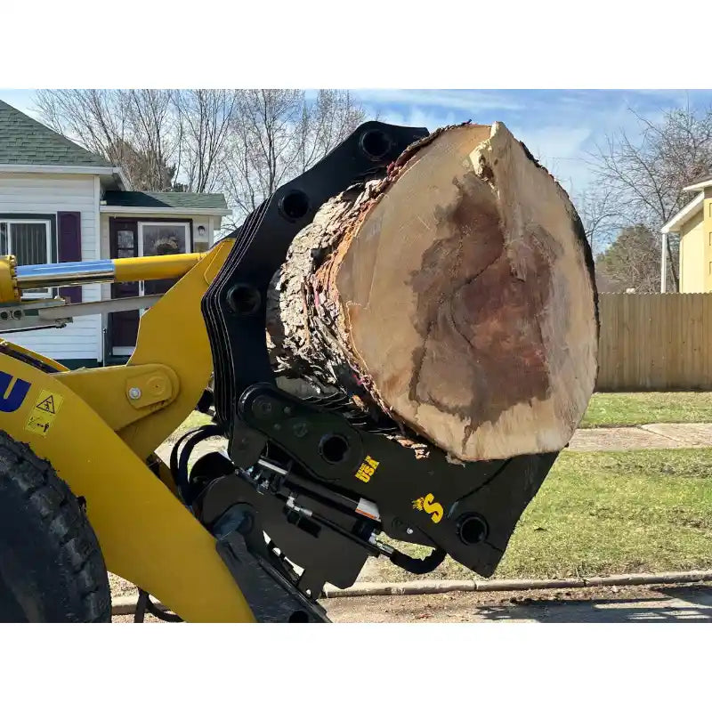 Yellow loader equipped with black hydraulic clam-style grapple attachment holding large cut tree log outdoors