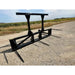 Black steel loader attachment with five pointed bale spears and reinforced frame on gravel surface outdoors