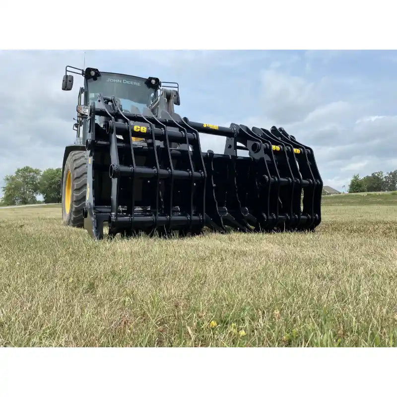 Black steel tractor clam grapple attachment mounted on a yellow John Deere tractor on grassy field under cloudy sky