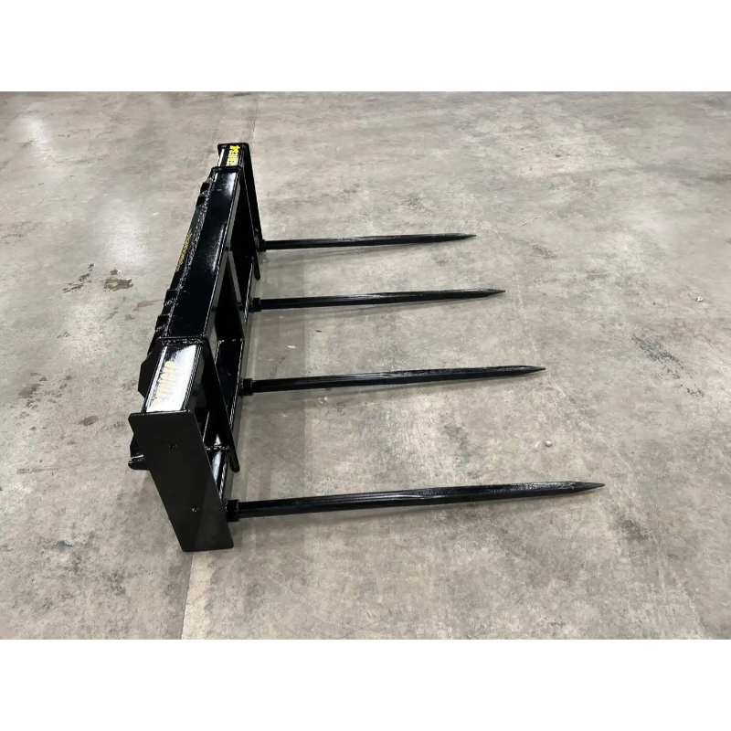 Black steel skid steer bale spear attachment with four long pointed tines on concrete floor viewed from side angle