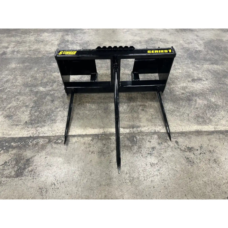 Black metal skid steer attachment with three pointed tines on concrete floor labeled Series 1 and Stinger