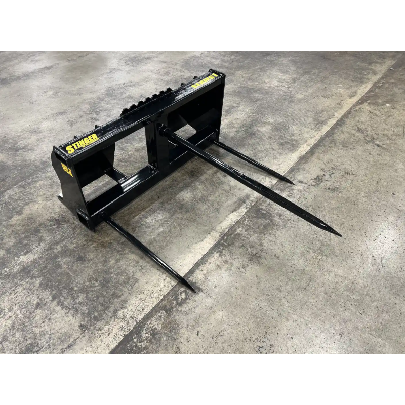 Black skid steer bale spear attachment with three long pointed spears on concrete floor