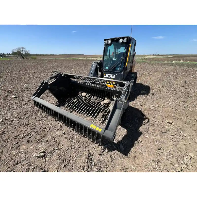 Front view of skid steer with rock bucket reel attachment on dry soil under clear blue sky