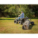 Rear view of operator on ATV using Swisher log skidder to haul large timber across grass, gallery position 1