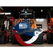 Rotating grapple attachment with red, black, and white curved steel claws and American flag decal on blue mounting plate
