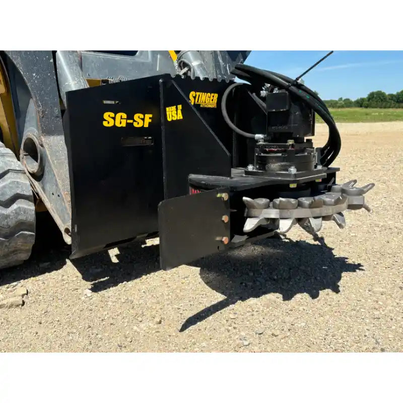 Black skid steer stump grinder attachment with multiple steel cutting teeth and hydraulic hoses on gravel surface