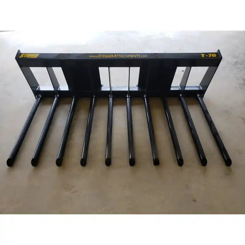 Black steel tine attachment with ten long, tubular tines spaced evenly across a rectangular frame on concrete floor