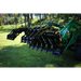 Open black steel grapple attachment mounted on green tractor with visible hydraulic arms on grass outdoors