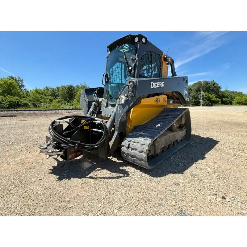 John Deere compact track loader with skid steer stump grinder attachment and hydraulic hoses on gravel surface