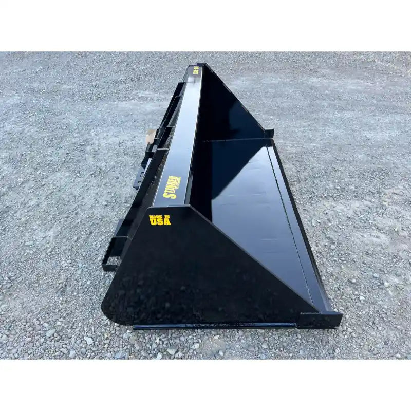 Glossy black steel tractor bucket attachment with reinforced sides and mounting brackets resting on gravel surface outdoors
