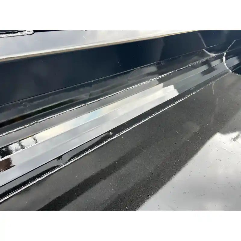Close-up of smooth black steel skid steer bucket interior showing weld seams and reflective surfaces