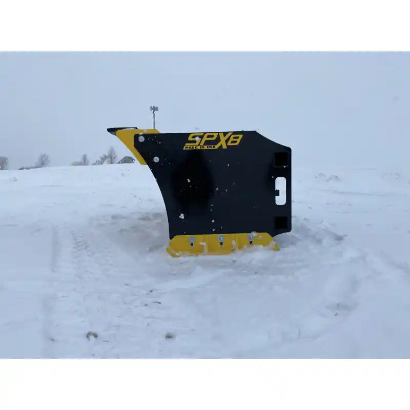 Side profile of a black and yellow skid steer snow pusher attachment positioned on snow-covered ground outdoors