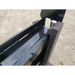 Close-up of black painted steel forklift attachment mounting plate with locking pin and channel on gravel surface