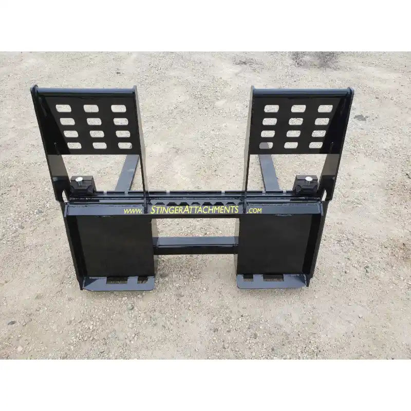 Black steel pallet fork attachment with backrest and mounting brackets on gravel surface