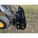 Right-side view of black steel clam grapple attachment mounted on yellow skid steer loader on dirt ground outdoors