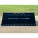 Black metal snow bucket attachment with cutting edge and ventilation slots on gravel surface